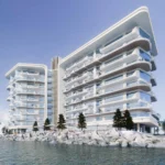 Modern waterfront view of Fortune Bay, featuring sleek glass-fronted residences by the shoreline.