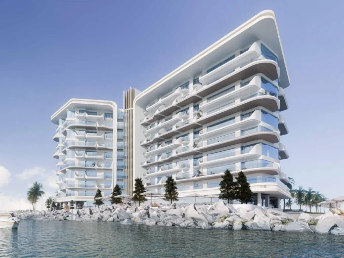 Modern waterfront view of Fortune Bay, featuring sleek glass-fronted residences by the shoreline.