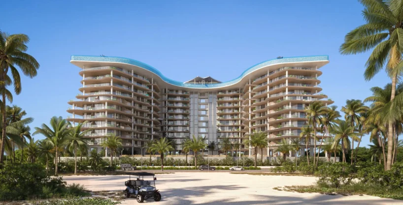 A striking, multi-story Manta Bay resort building with a curved, wave-like roof and rooftop pools.