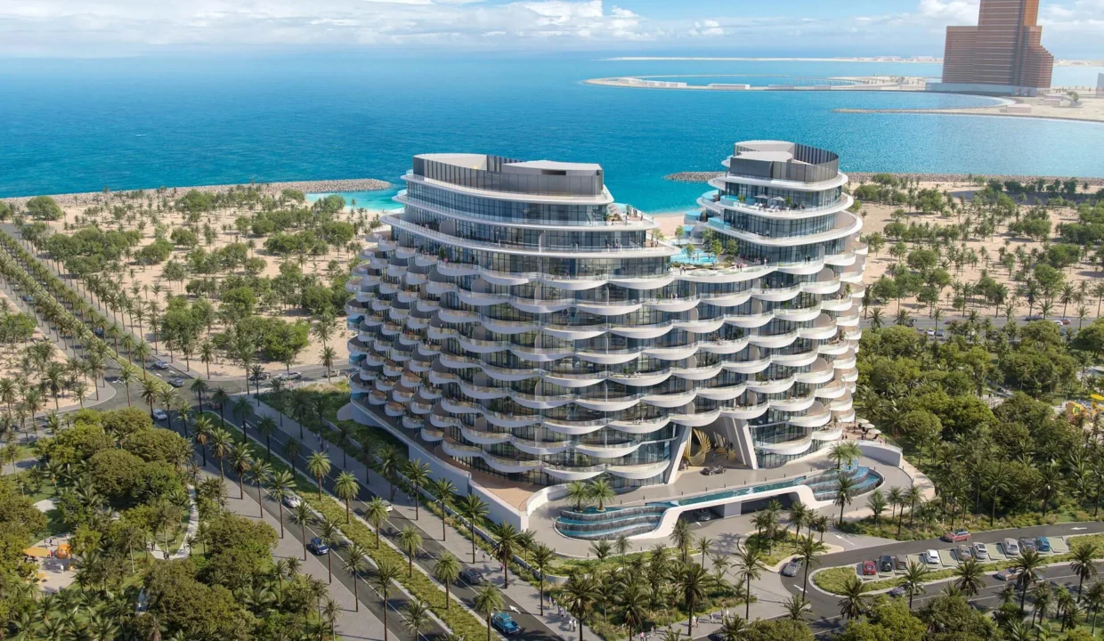 "Aqua Arc," a pair of curved, modern buildings, stands near a coastline with blue water and lush greenery.