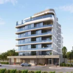 A modern, multi-story building, "Aquino by BNW Developments", with glass balconies, on a sunny street.