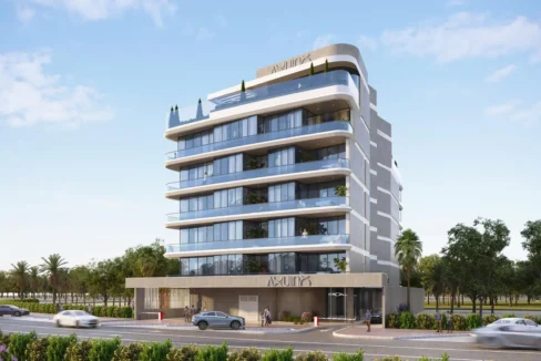 A modern, multi-story building, "Aquino by BNW Developments", with glass balconies, on a sunny street.