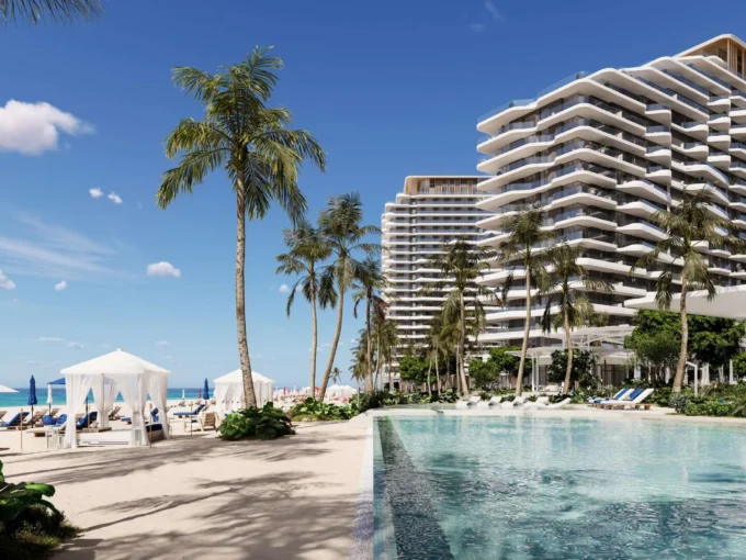 A sunny beach scene at Nikki Beach with palm trees, a swimming pool, and modern buildings.