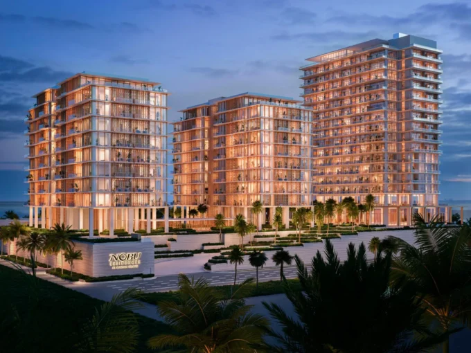 Night view of Nobu Residences towers glowing with warm lights near the beach on Al Marjan Island.