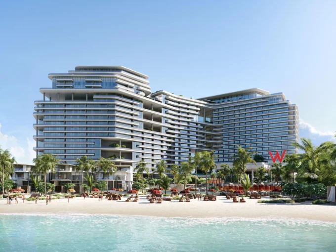 A sprawling W Residences complex with multiple balconies overlooks a beach with palm trees and sunbeds.